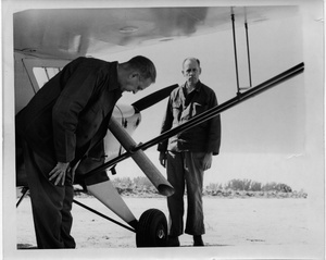 Thumbnail for the first (or only) page of Photograph of researchers inspecting airplane chute for fly release.